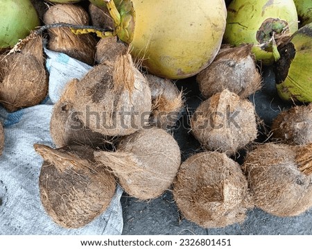 Old coconuts that have been peeled and some fruit that is still intact.