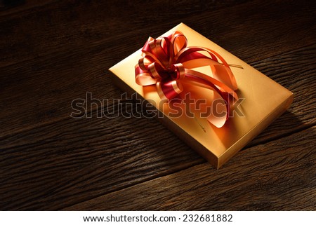 Gift box with ribbon on old wooden background