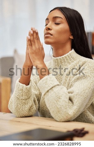 Religion, prayer and young woman in her living room with christian faith, gratitude and worship. Spiritual, hope and religious female person praying with her hands together to god in her modern home.