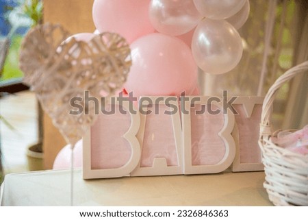 Plastic sign words Baby in pink for a child's baptism. Pink decorations and balloons around the sign. High quality photo
