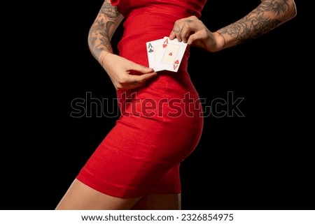 Slender woman in red dress holding pair of winning aces