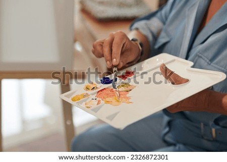Closeup image of woman mixing colors on plastic palette Royalty-Free Stock Photo #2326872301