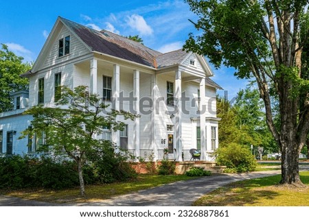 A Wooden Classic Revival Style House with Columns and Front Porch in Southern USA. Royalty-Free Stock Photo #2326887861