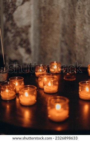 Picture of Easter candles burning at night with golden light of candle flame. Lampion candles glowing in a dark church. Emotional mood. Many burning candles with shallow depth of field
