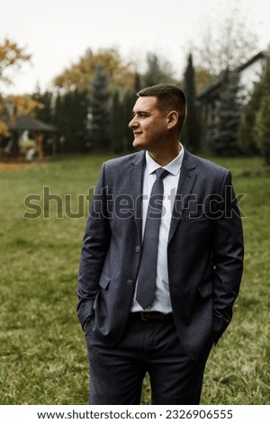 portrait of the groom outside in the autumn season.stylish tall groom in a blue suit.businessman in nature. portrait of a successful man Royalty-Free Stock Photo #2326906555