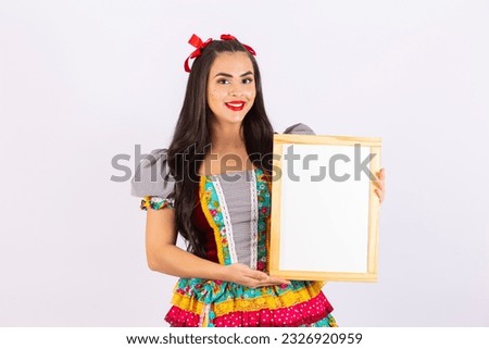 Young woman dressed in typical festa junina outfit holding a blank mockup with free space for text