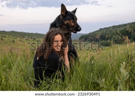 Back view photo of a woman enjoying time with her dog in the field.