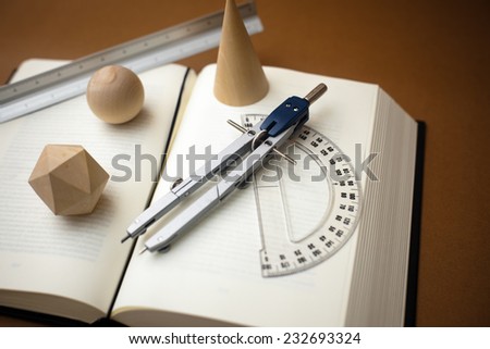 Wooden geometric shapes and drawing tools on a book.