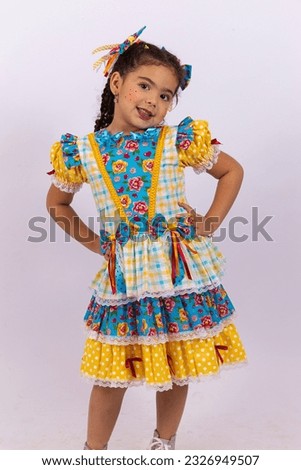 Little girl with curly hair dressed in festa junina costume smiling at camera with free space for text. Vertical