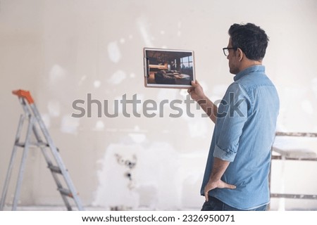 Home owner standing in unfinished premise looks at picture with interior design in loft style against ladder near wall man in glasses imagining apartment after renovation process