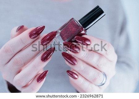 Woman hand with long nails and a dark red bordeaux nail polish 