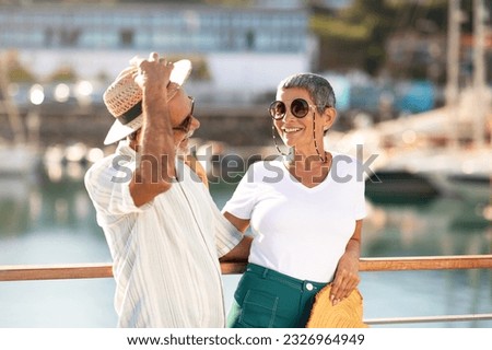 Golden Summer. Joyful Senior Man Holding Straw Hat And Hugging Wife, Posing Together At Marina Pier With Yachts And Luxury Sailboats, Laughing And Flirting Enjoying Sunny Day On Vacation Outdoor Royalty-Free Stock Photo #2326964949