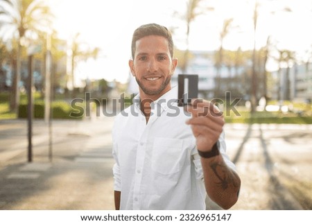 Bank offer. Portrait of happy european bank worker showing credit card to camera and smiling, standing outdoors and advertising financial service