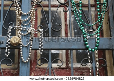 Colorful strands of green and silver Mardi Gras beads are draped on a wrought iron railing, French Quarter, New Orleans.