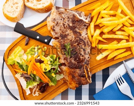 narrow slice of toasted entrecote is garnished with French fries and vegetables Royalty-Free Stock Photo #2326991543