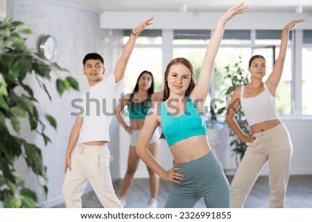 Positive female teenager engage house dance in choreographic school, group of young people in sportswear trains together with their classmates in gym before competitions, battle