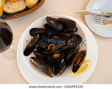 Picture of steamed tasty mussels served on pan with lemon, tapas of spanish cuisine