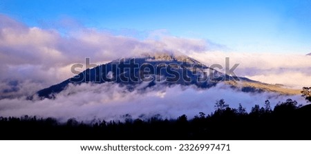 View of Mount Raung covered in morning mist against a blue sky in the background, Banyuwangi, Indonesia