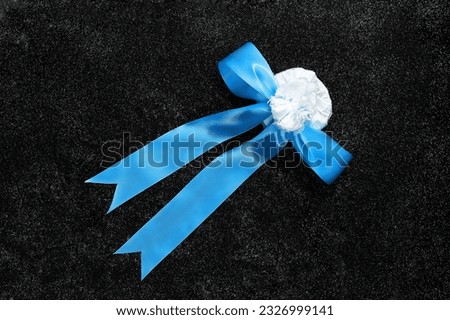 A small gift in a white round box with a big blue bow , on a black table . Surprise for a loved one.