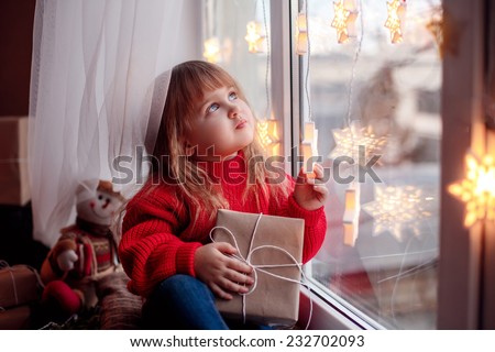 happy baby sitting on the window with Christmas present