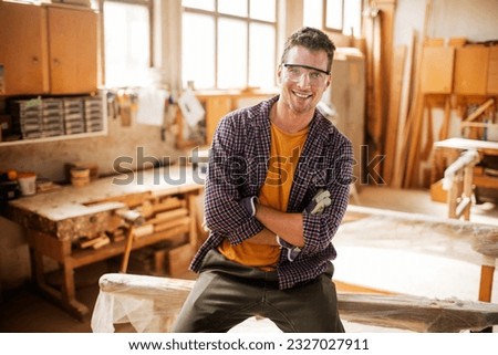 Portrait of a young carpenter looking at the camera in his woodworking workshop Royalty-Free Stock Photo #2327027911