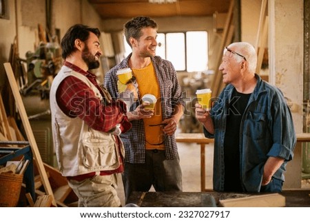 Small group of carpenters enjoying a cold bottle of beer after a hard days of work in their woodworking workshop