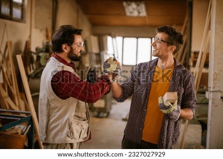 Carpenters high fiving after a finished job in their woodworking workshop Royalty-Free Stock Photo #2327027929