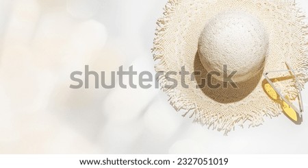 Summer flat lay straw sun hat and yellow sunglasses at sunlight on  light grey background with blurred bokeh glare as copy space. Aesthetic Life style summer holidays photo, beige pastel color banner Royalty-Free Stock Photo #2327051019