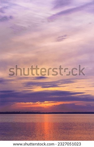 Colorful sky background on sunset, orange blue vivid color clouds and surface water on lake Ik. Nature abstract fon with reflections on water, natural shades cloudscape, nature environment screensaver