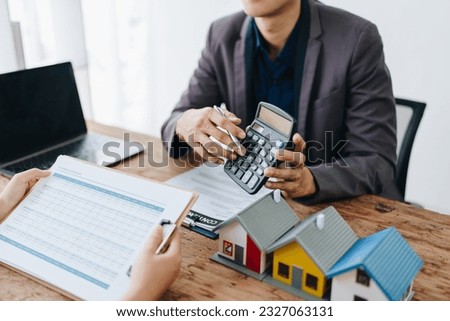 Guarantee, mortgage, contract, contract, signed, real estate agent or bank officer holding a calculator, submits a bid with a customer to buy a home before signing to make a deal.