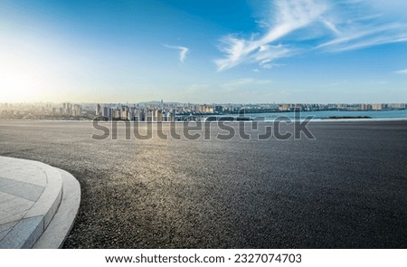 Asphalt road and urban skyline with sky clouds at sunset