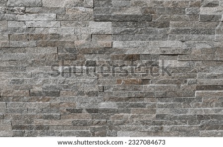 Stone cladding wall made of striped stacked bricks of gray 
 and brown rocks. Panels for exterior, background and texture. Royalty-Free Stock Photo #2327084673