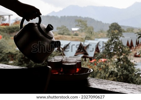 brewing hot tea in a traditional teapot against a rural setting early in the morning