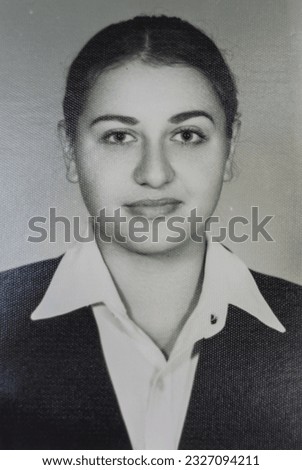 Old black and white photograph on photographic paper from the 80s. Example of a passport photo. Young female model with a white background. An example of a photograph of a degree certificate