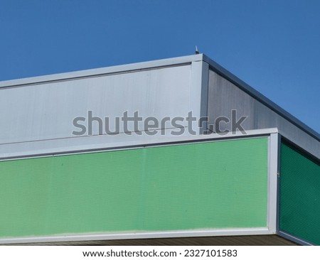 Part of the building. Colorful roof. Green and silver colors. Blue sky, background.