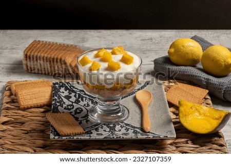Delicious glass of cold yogurt mousse with mango and biscuit, dark food style. Horizontal photo for recipe or menu and selective focus