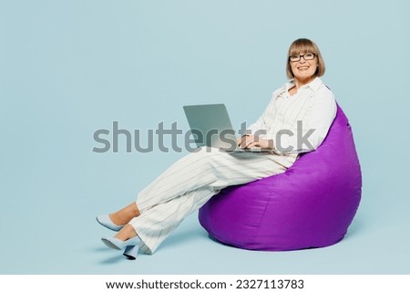 Full body employee IT business woman 50s wears white classic suit glasses formal clothes hold use work on laptop pc computer isolated on plain pastel light blue background. Achievement career concept