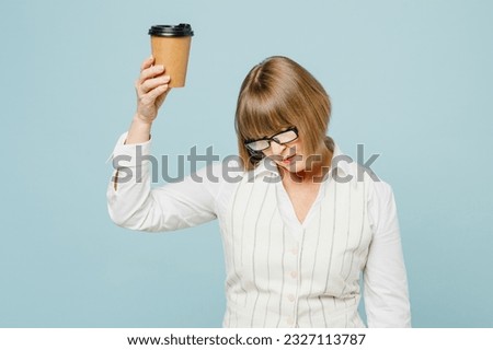 Tired employee business woman 50s wear white classic suit glasses formal clothes hold takeaway delivery craft paper brown cup coffee to go isolated on plain blue background. Achievement career concept