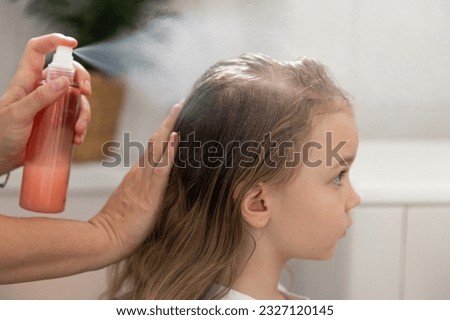 Women's hands apply a remedy for lice and nits on the head of a little girl. Getting rid of parasites and pests, childhood diseases. High quality 4k footage