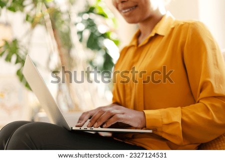 Smiling African American business woman, freelancer, copywriter typing on keyboard working online, planning project sitting in modern office. Female shopping online, ordering food, selective focus