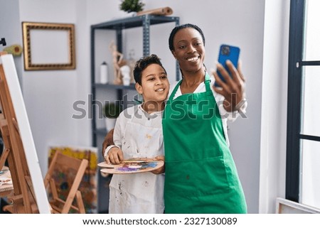 African american mother and son art student and teacher making selfie by smartphone at art studio