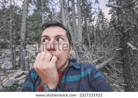 A frightened and lost male hiker looks around in the forest. The concept of meeting wild animals and phobia and accident in the woods Royalty-Free Stock Photo #2327131923