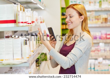Youn woman comparing prices with her smartphone in drugstore department of a supermarket