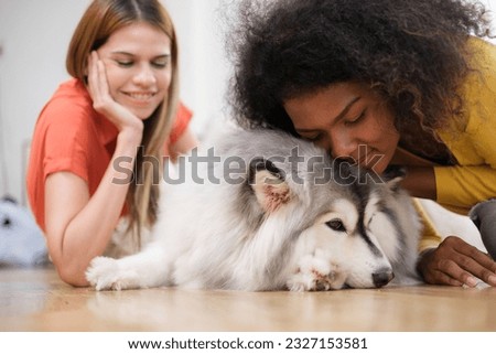 Happy multiracial female couple with cute Siberian Husky  dog enjoying free time together at home