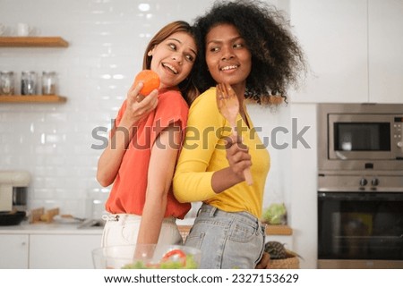 Multiracial Lesbian couple cooking salad in kitchen
