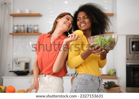 Multiracial Lesbian couple cooking salad in kitchen
