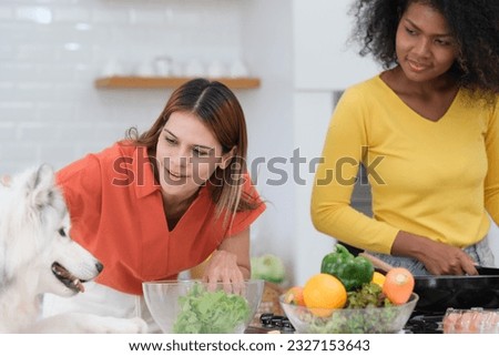Multiracial Lesbian couple enjoy cooking salad with her dog in kitchen
