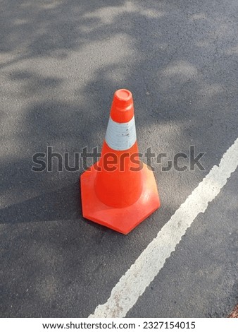bright orange traffic cone standing on dark asphalt