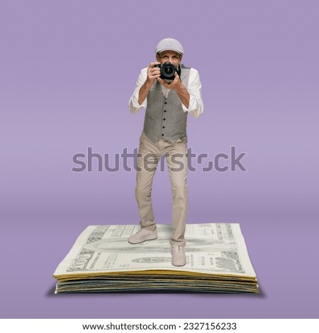 Male photographer with modern camera taking photo on pile of money banknotes