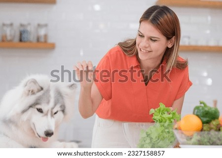 Multiracial Lesbian couple enjoy cooking salad with her dog in kitchen